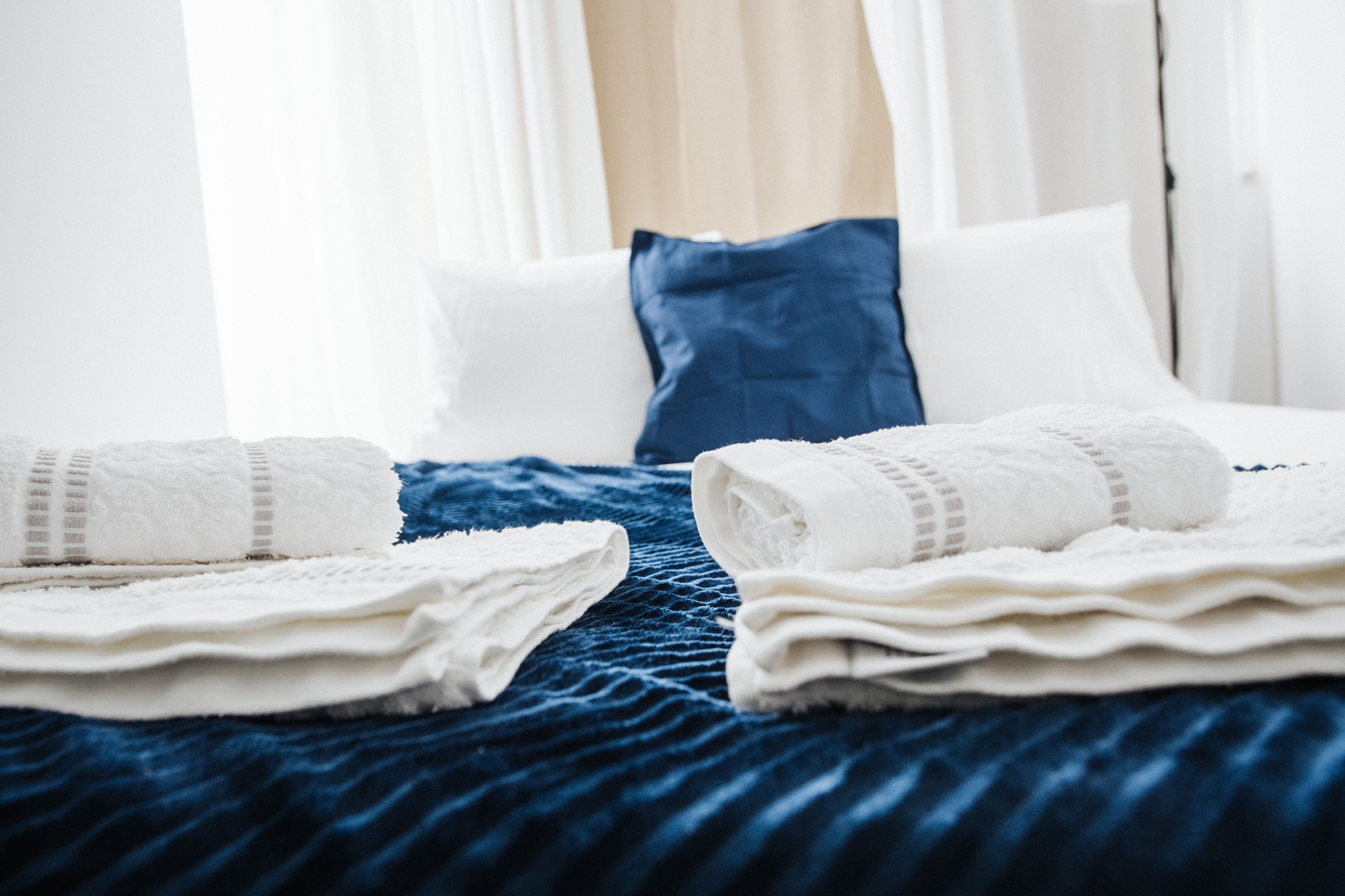 Fresh white towels arranged on a neatly made guest bed