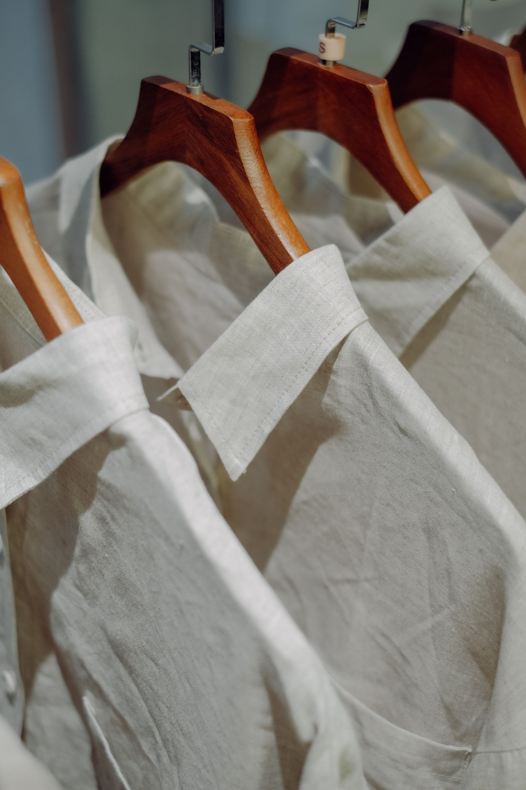 Crisp white collared shirts arranged on wooden hangers
